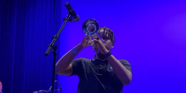 Student trumpet player under blue stage lights